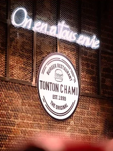 Néon « On en a tous envie » au-dessus du logo Tonton Chami
