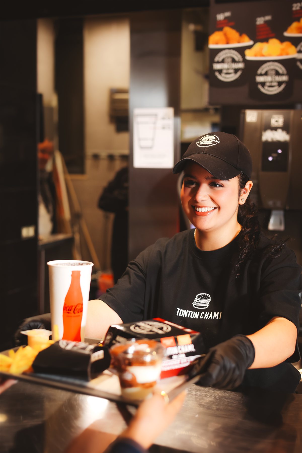 Équipière Tonton Chami souriante au comptoir