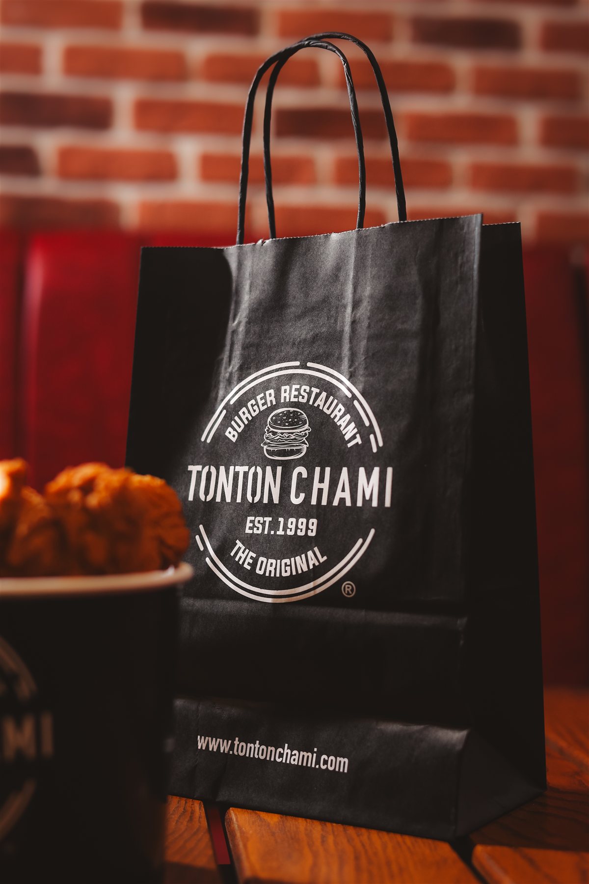 Sac Tonton Chami et bucket de poulet devant un mur de briques