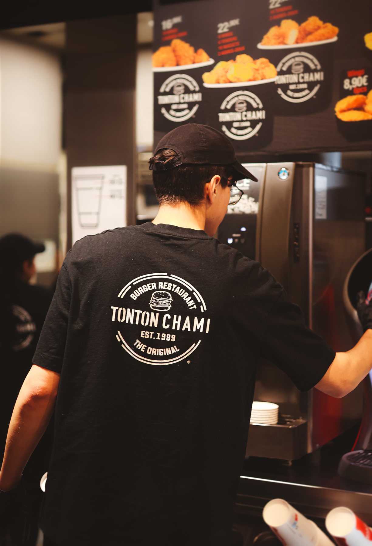 Équipier Tonton Chami en cuisine, logo de la marque dans le dos