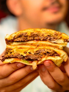 Double smash burger Tonton Chami tenu à deux mains