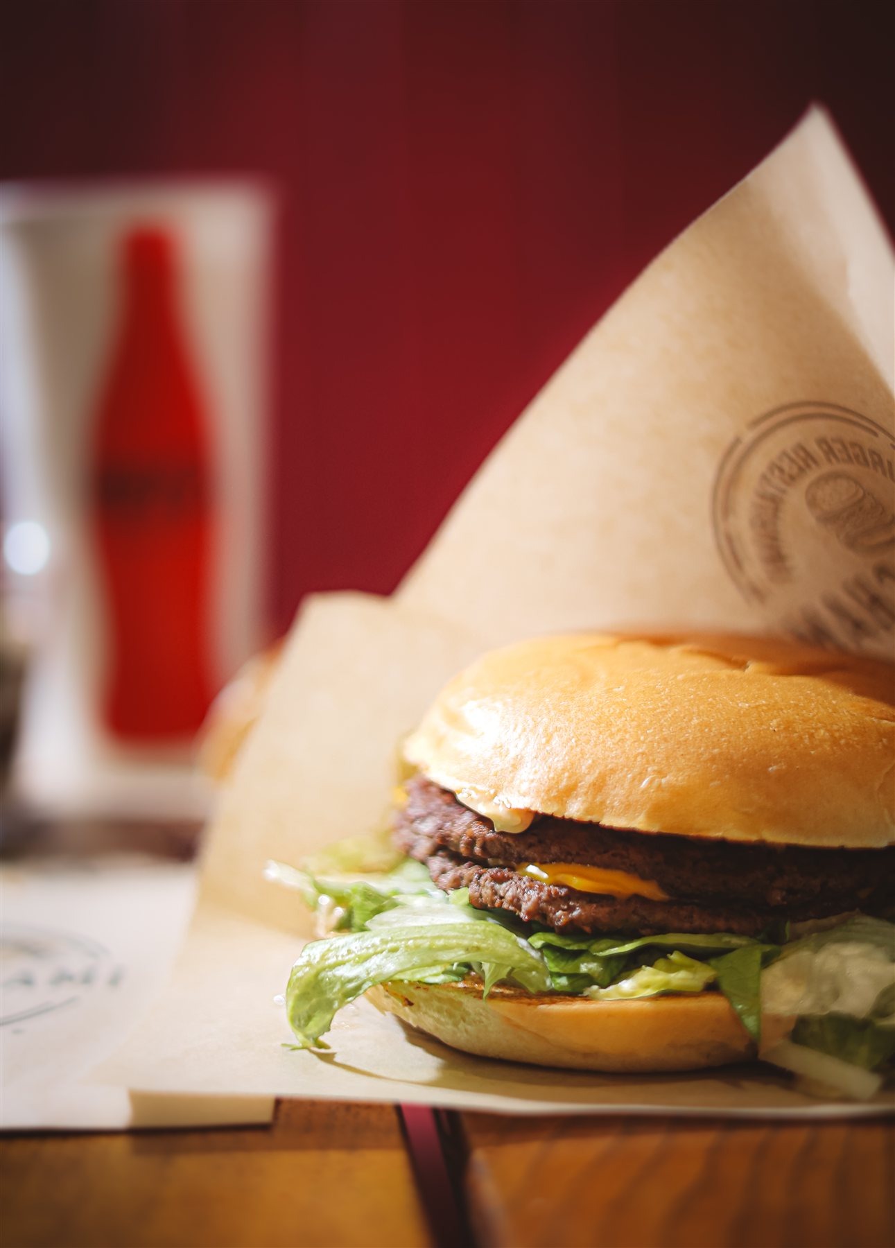 Burger Tonton Chami servi dans son papier, banquette rouge en fond